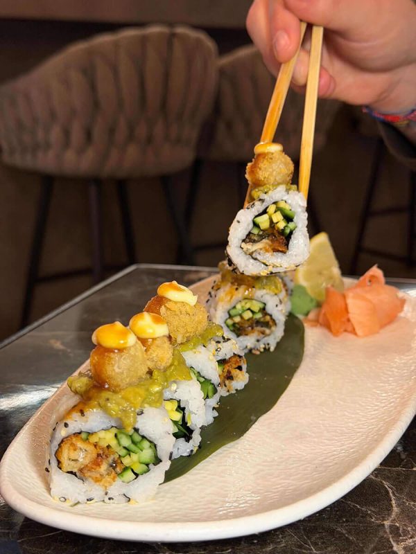 Person eating sushi roll with chopsticks