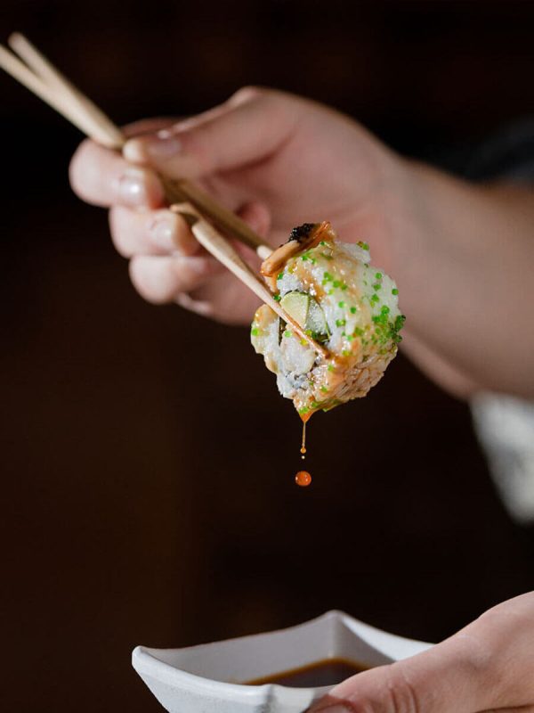 Woman eating sushi roll dipped in soya