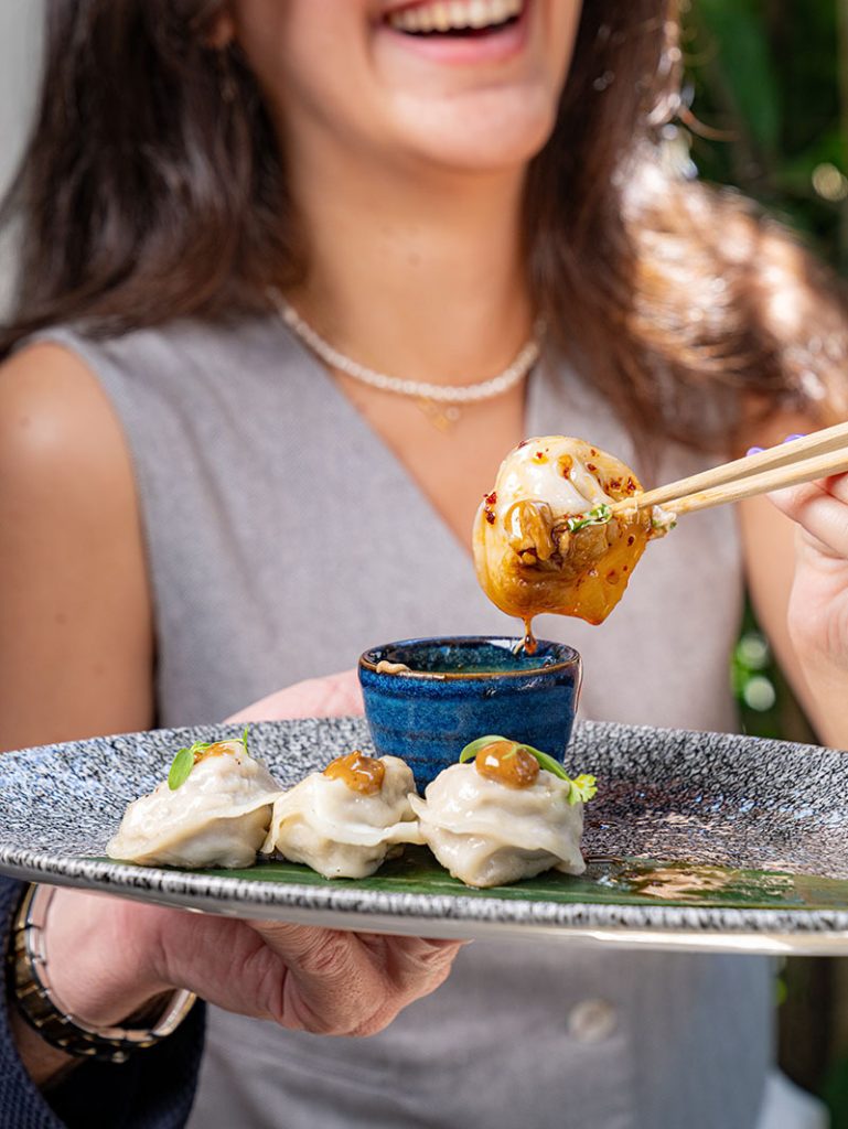 Woman eating asian food dipped in sauce