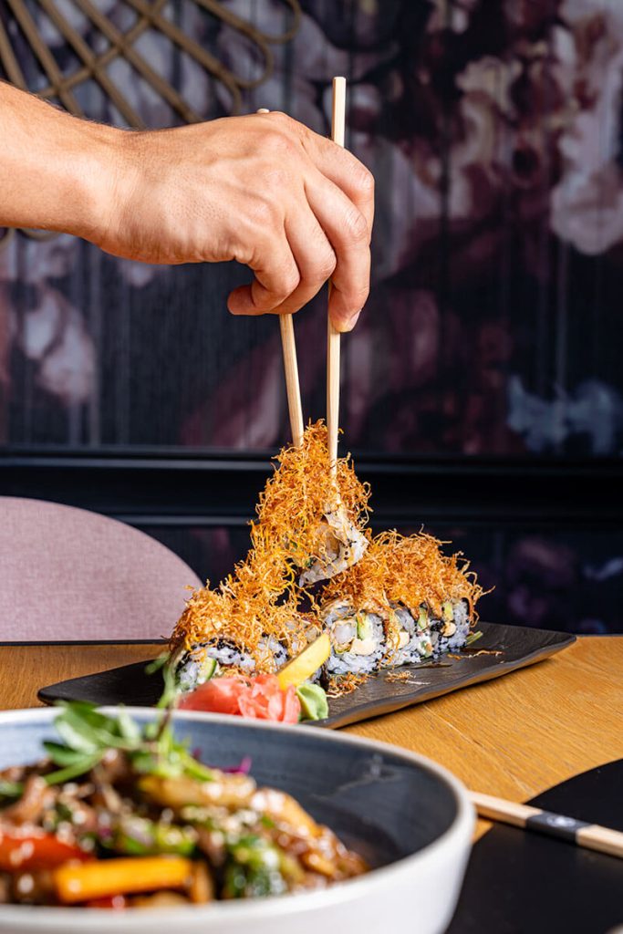 Person is eating with chopsticks sushi