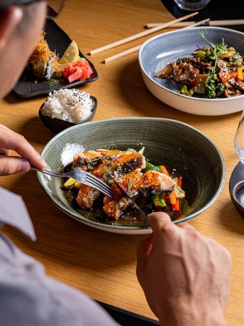 Man eating asian food with lots of side dishes
