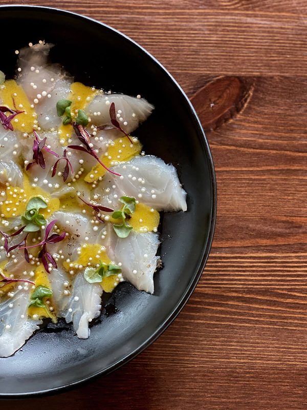 Raw fish plated on a dish with sauce